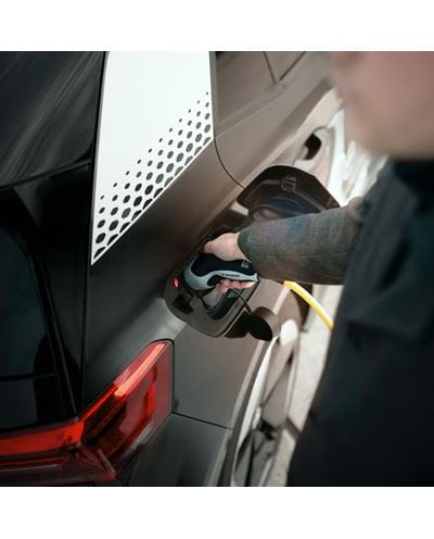 Persona a la derecha enchufando un coche eléctrico.